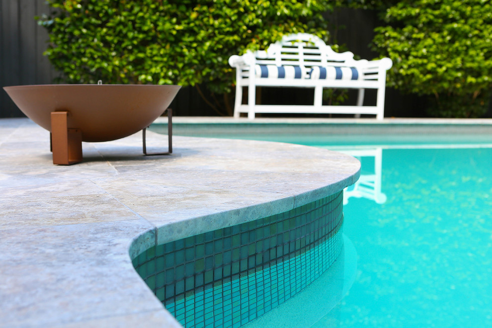 Ejemplo de piscina actual en patio trasero con adoquines de piedra natural