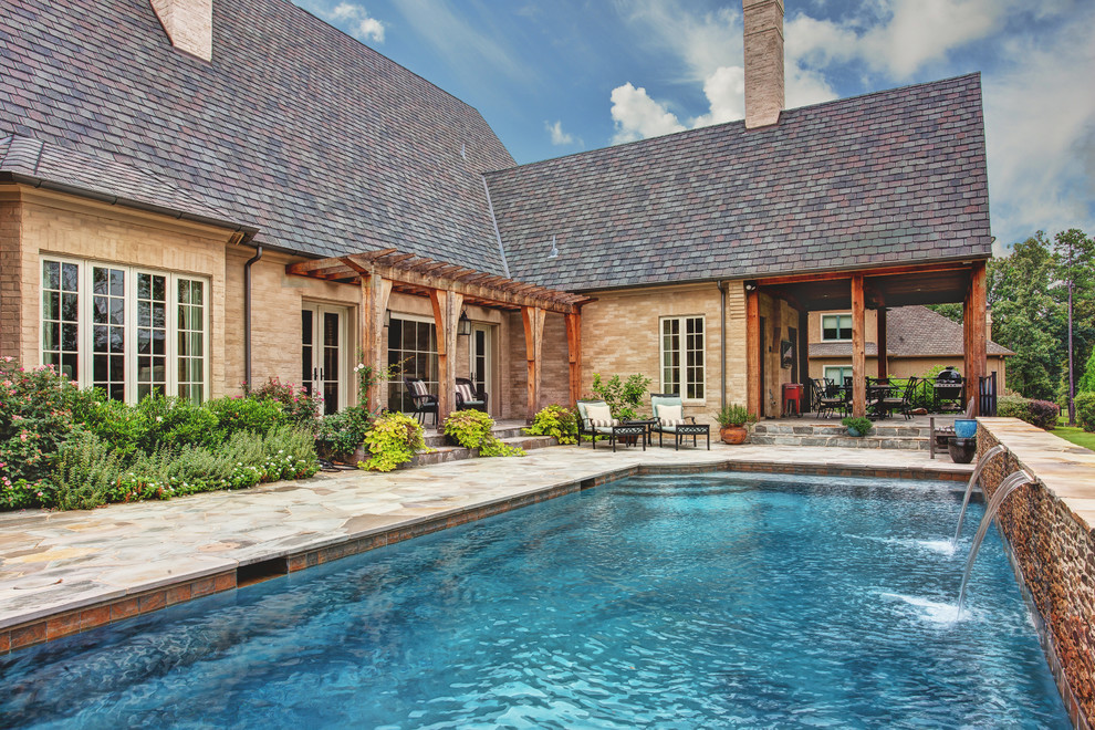 Esempio di una grande piscina fuori terra classica rettangolare dietro casa con fontane e piastrelle