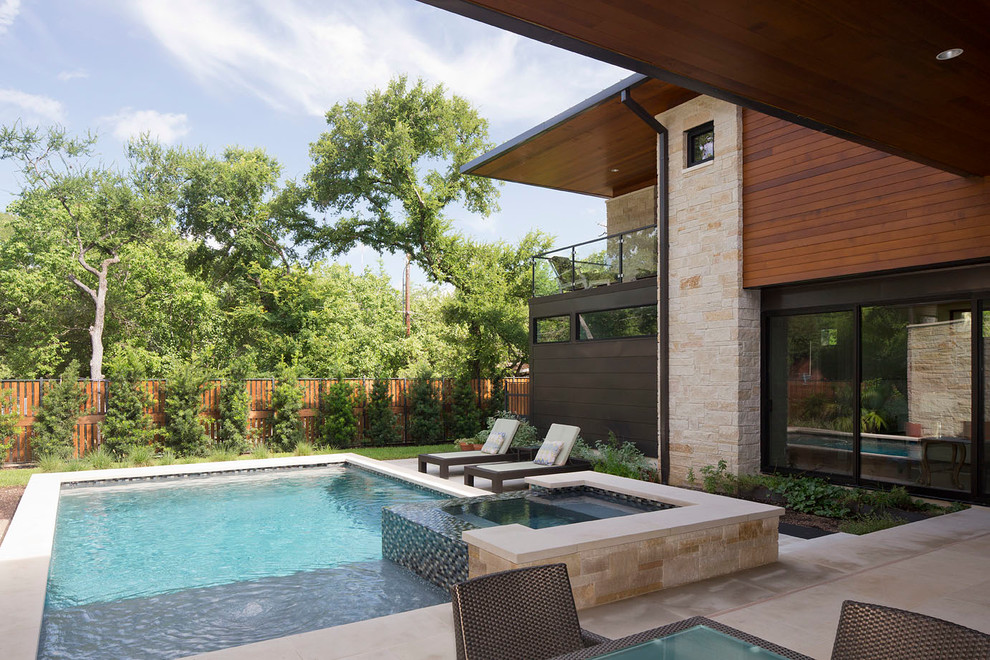 Imagen de piscinas y jacuzzis actuales rectangulares en patio trasero con adoquines de piedra natural