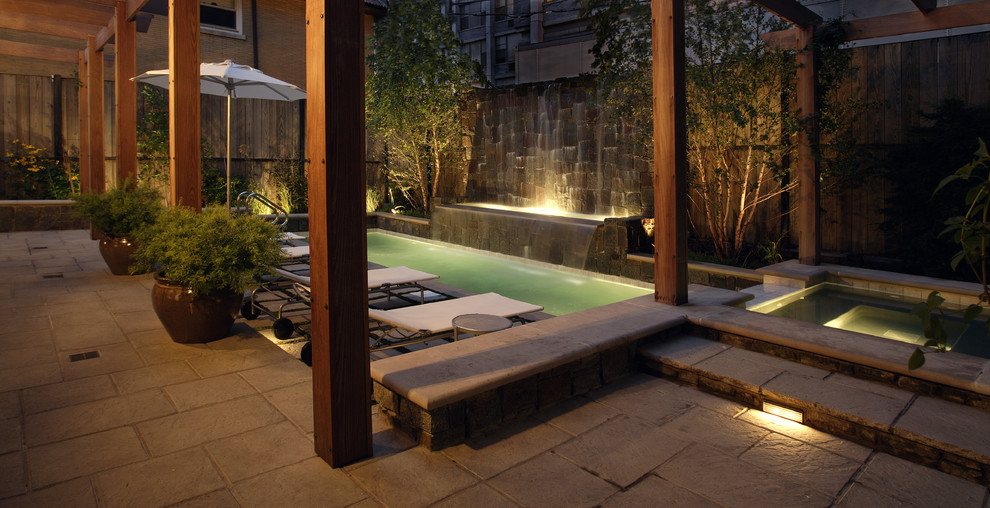 Esempio di una piccola piscina monocorsia minimalista rettangolare in cortile con pavimentazioni in pietra naturale e una vasca idromassaggio