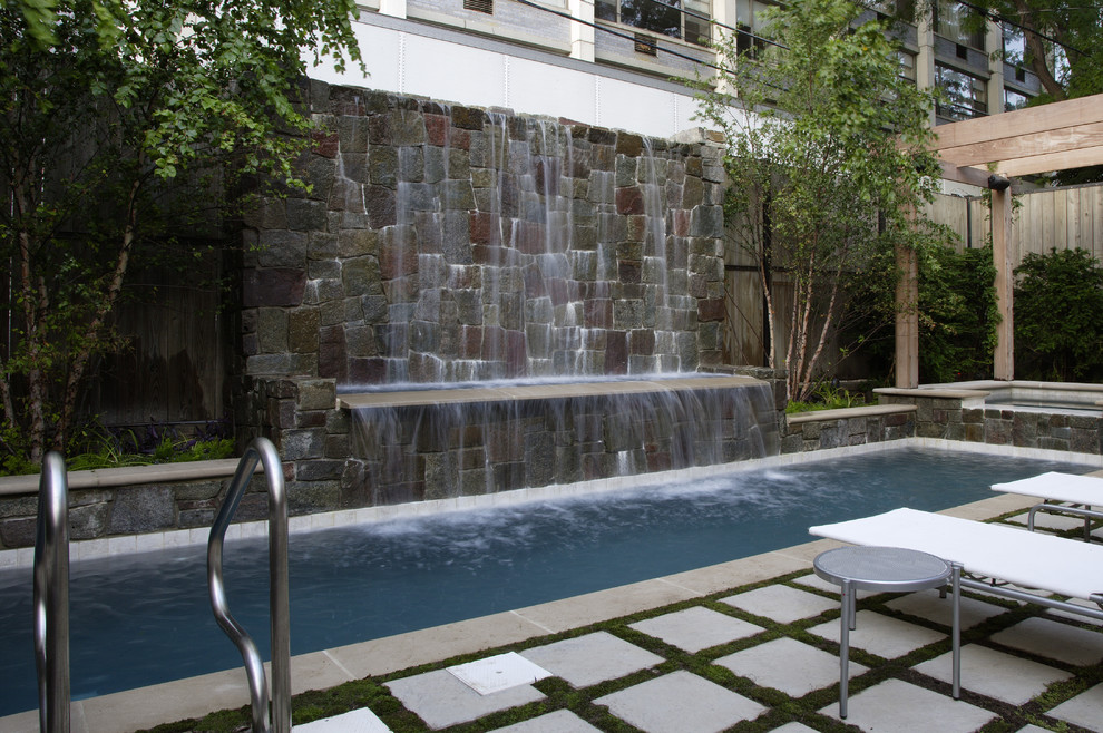 Esempio di una piccola piscina monocorsia minimalista rettangolare in cortile con pavimentazioni in pietra naturale e una vasca idromassaggio