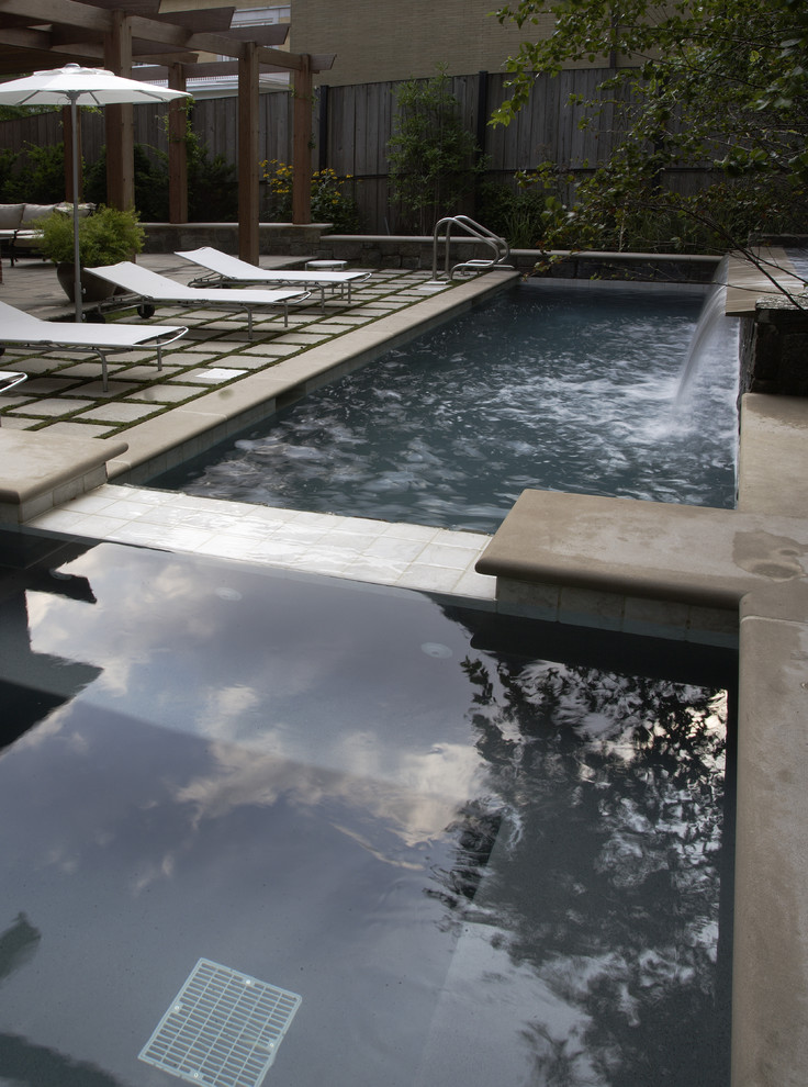 Foto di una piccola piscina monocorsia minimalista rettangolare in cortile con pavimentazioni in pietra naturale e una vasca idromassaggio