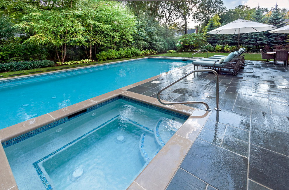 Immagine di una piscina tradizionale rettangolare di medie dimensioni e dietro casa con pavimentazioni in pietra naturale