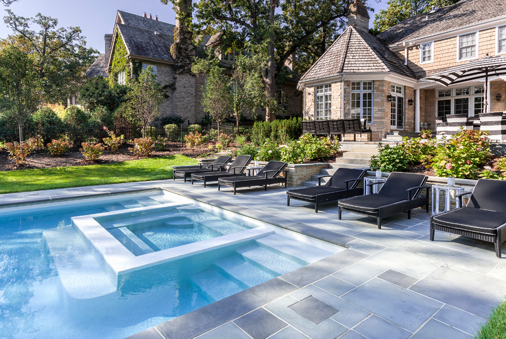 Immagine di una grande piscina tradizionale rettangolare dietro casa con pavimentazioni in pietra naturale