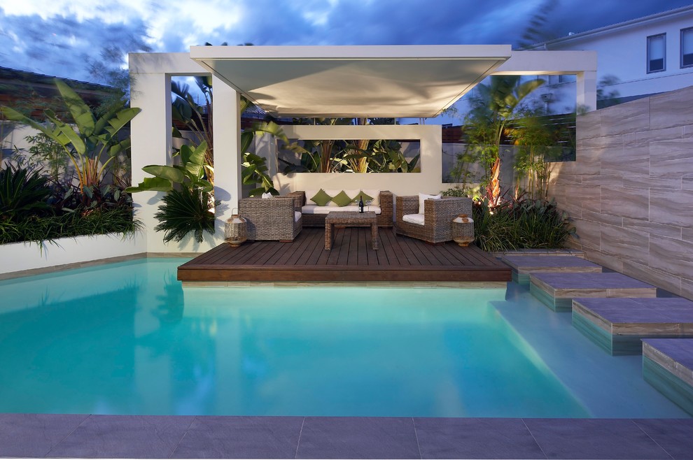 Пример оригинального дизайна: бассейн произвольной формы, среднего размера на заднем дворе в современном стиле с настилом