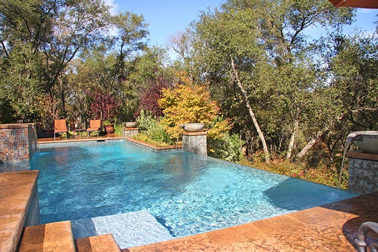 Ispirazione per una grande piscina a sfioro infinito mediterranea rettangolare dietro casa con pavimentazioni in pietra naturale