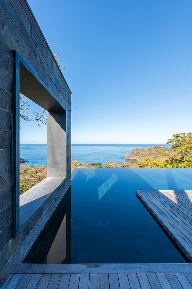 Exemple d'une très grande piscine à débordement tendance rectangle avec une terrasse en bois.