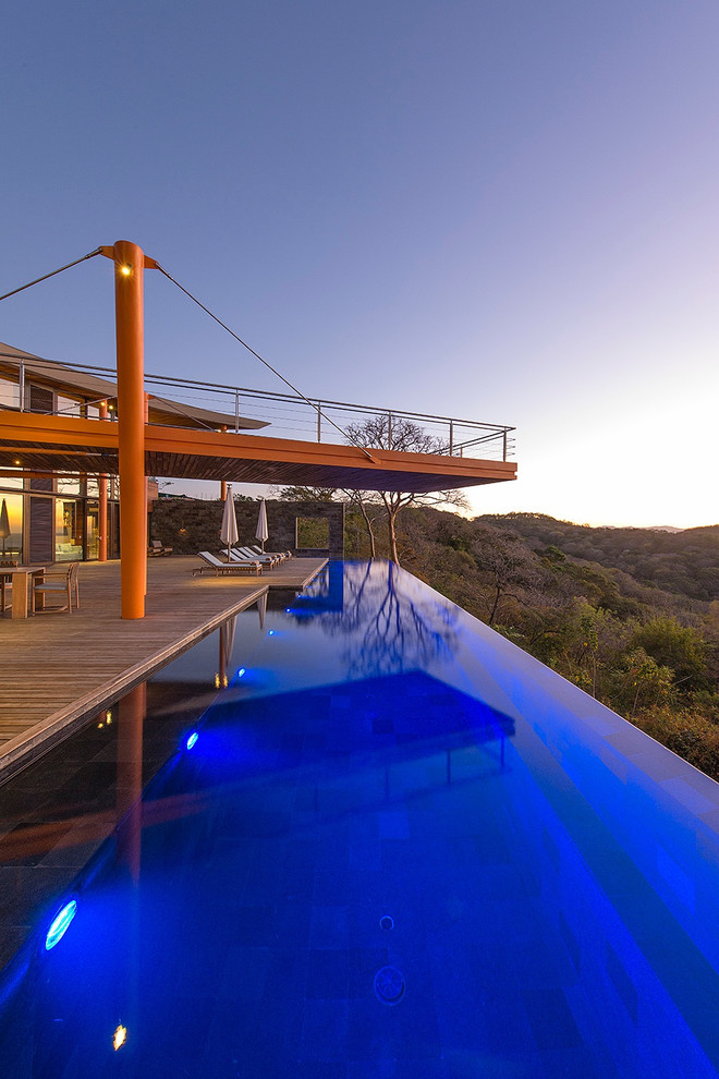 Aménagement d'une très grande piscine sur toit à débordement contemporaine rectangle avec une terrasse en bois.