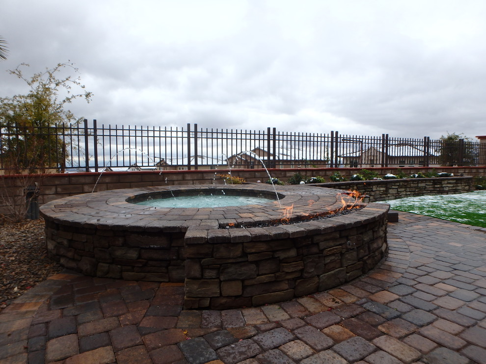 Design ideas for a small mediterranean back round hot tub in Las Vegas with brick paving.
