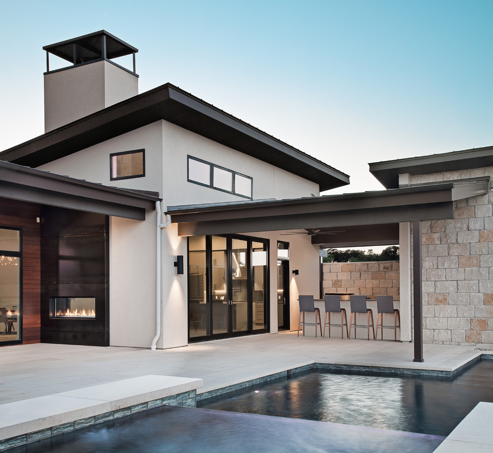 Ispirazione per una grande piscina monocorsia design rettangolare dietro casa con una vasca idromassaggio e pavimentazioni in cemento