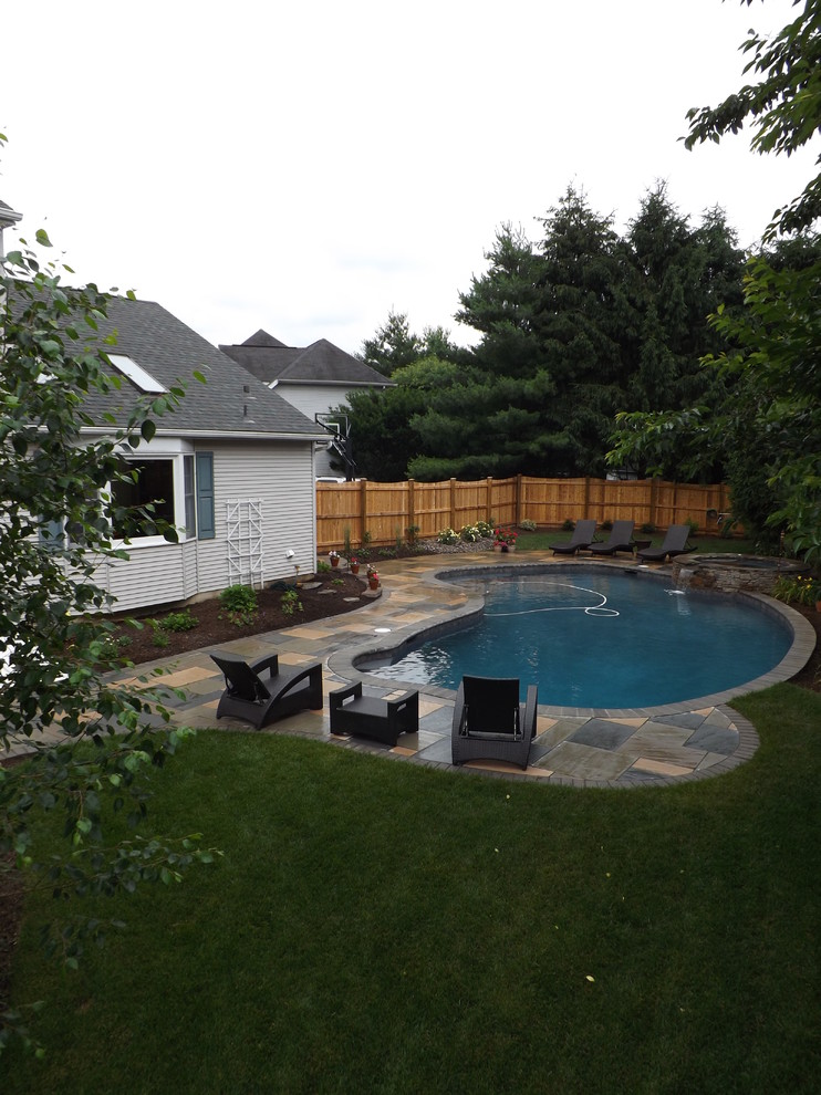 Источник вдохновения для домашнего уюта: большой бассейн в форме фасоли на заднем дворе в классическом стиле с джакузи и мощением тротуарной плиткой