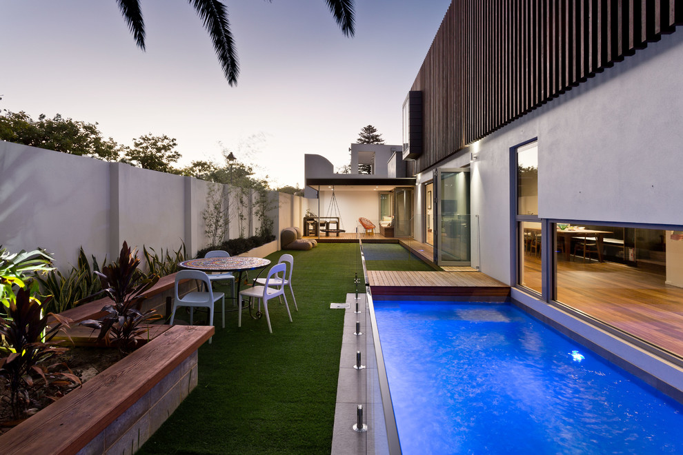 На фото: спортивный, прямоугольный бассейн на заднем дворе в современном стиле с настилом