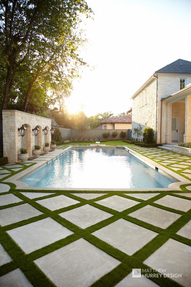 This is an example of a medium sized traditional back rectangular swimming pool in Dallas with a water feature and concrete slabs.