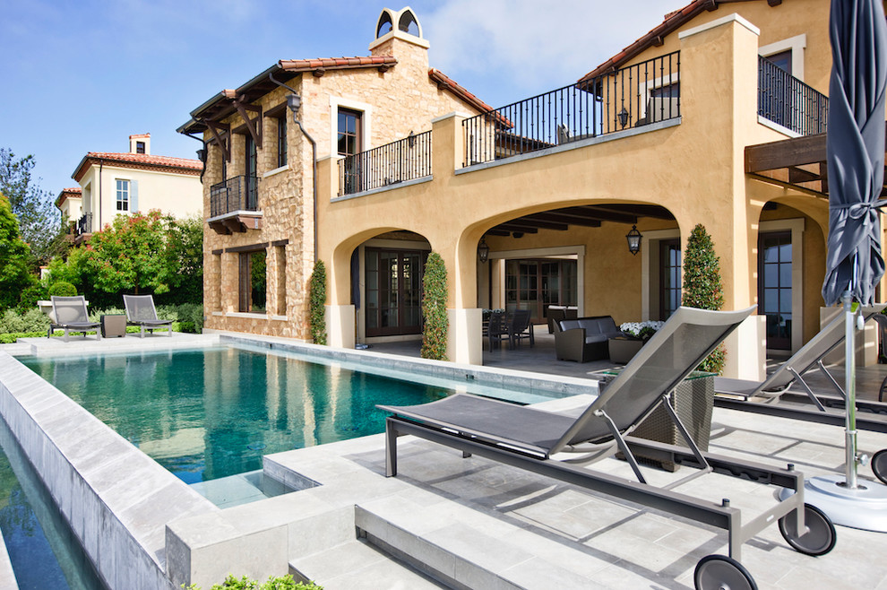 Ejemplo de piscina alargada mediterránea grande rectangular en patio trasero con adoquines de piedra natural