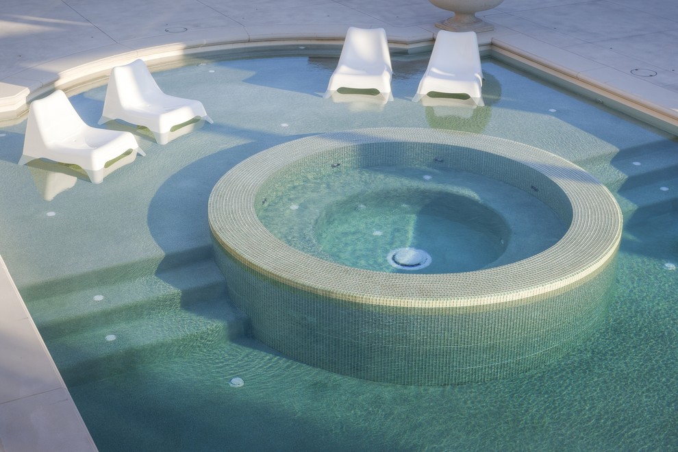 Aménagement d'une très grande piscine arrière contemporaine sur mesure avec un bain bouillonnant et du béton estampé.