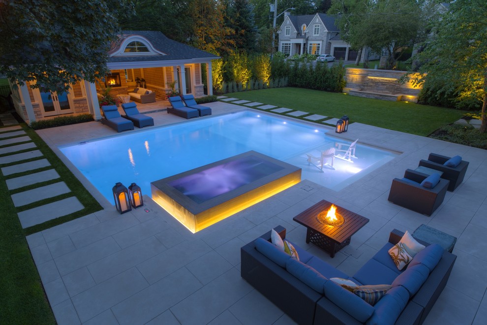 Modelo de casa de la piscina y piscina alargada actual de tamaño medio rectangular en patio lateral con losas de hormigón