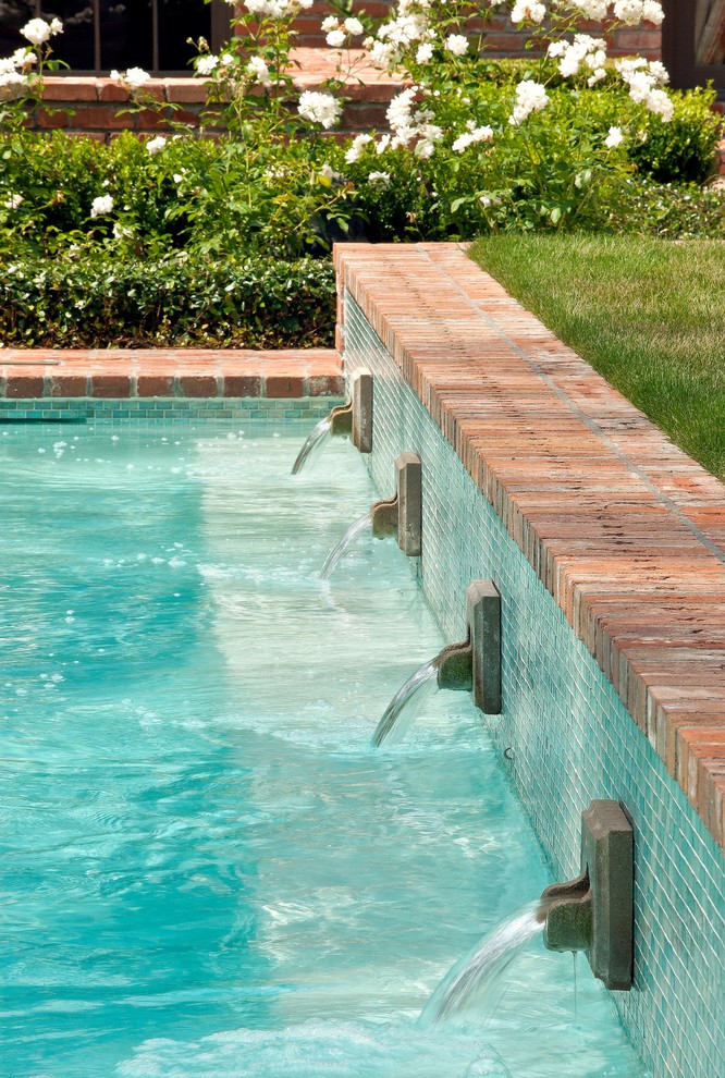 Example of a large classic backyard brick and rectangular lap pool fountain design in Houston