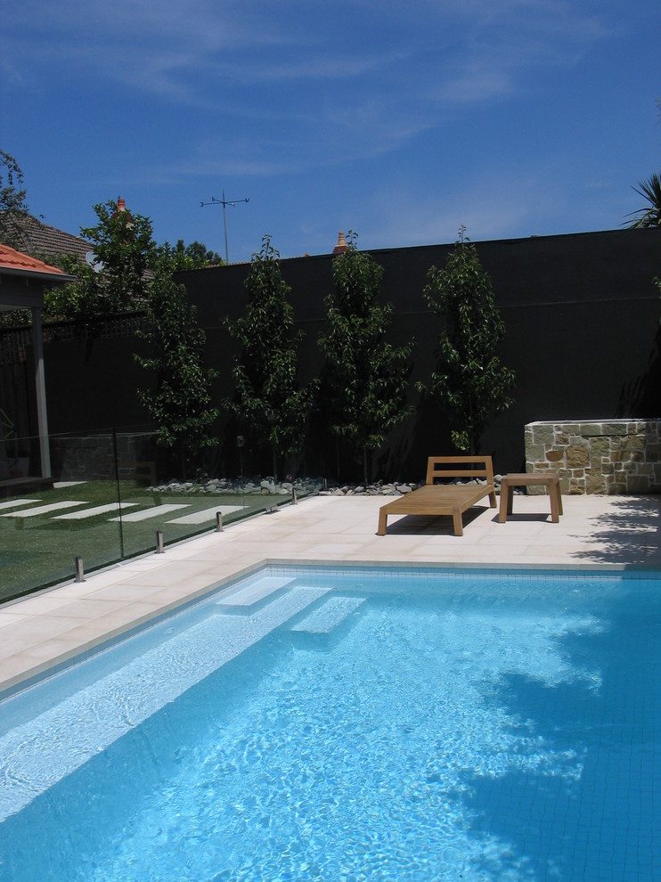 Diseño de piscina contemporánea pequeña rectangular en patio trasero con adoquines de hormigón