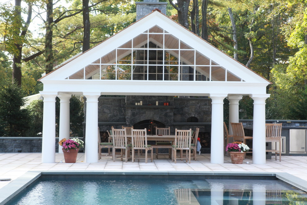 Ejemplo de casa de la piscina y piscina natural tradicional grande rectangular en patio trasero con adoquines de piedra natural