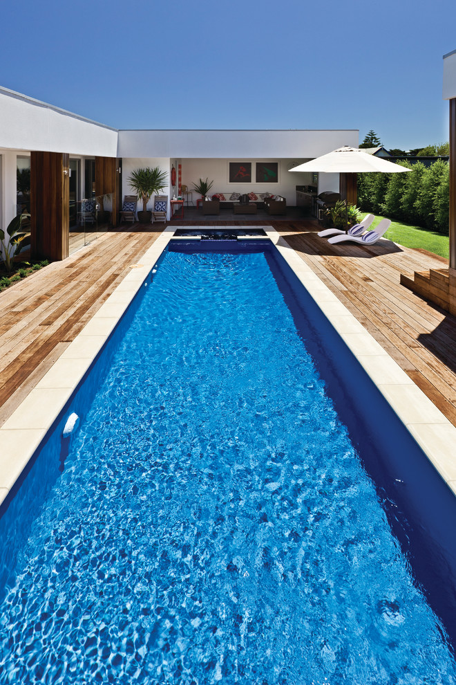Пример оригинального дизайна: большой спортивный, прямоугольный бассейн на заднем дворе в морском стиле с фонтаном и настилом