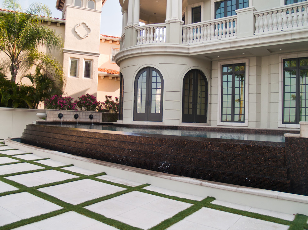 Huge trendy backyard concrete paver and custom-shaped infinity pool photo in Tampa