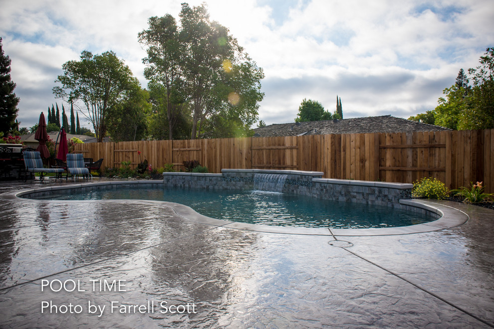Foto di una piscina minimalista a "C" di medie dimensioni e dietro casa con fontane e cemento stampato