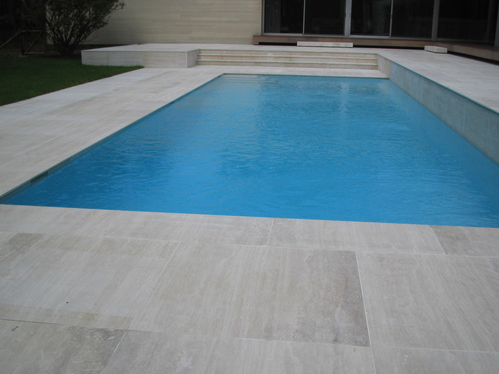 Exempel på en modern rektangulär pool på baksidan av huset, med kakelplattor