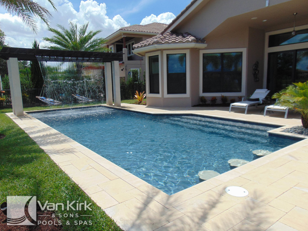 Foto de piscina con fuente natural actual grande rectangular en patio trasero con adoquines de piedra natural
