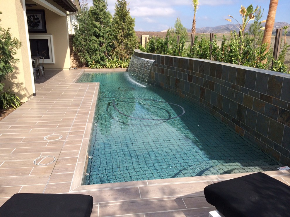 Inspiration for a small modern back rectangular natural swimming pool in Los Angeles with a water feature and tiled flooring.