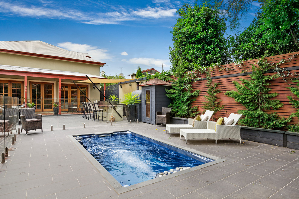 Modelo de piscina alargada clásica rectangular en patio trasero con adoquines de hormigón