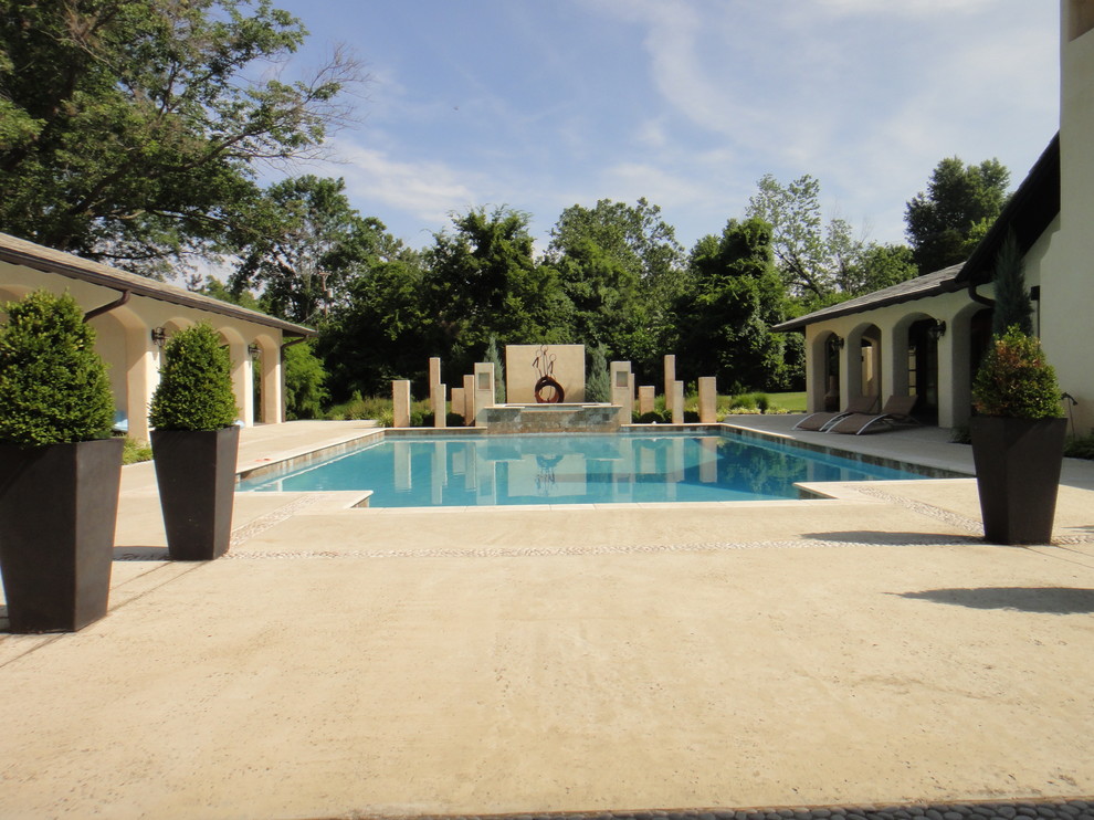 Esempio di una grande piscina coperta mediterranea rettangolare con fontane e lastre di cemento