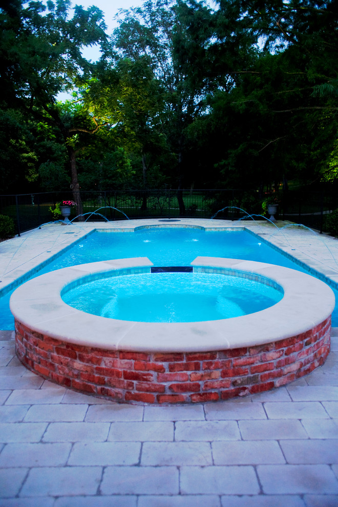 Cette photo montre une piscine arrière chic rectangle et de taille moyenne avec un bain bouillonnant et des pavés en pierre naturelle.
