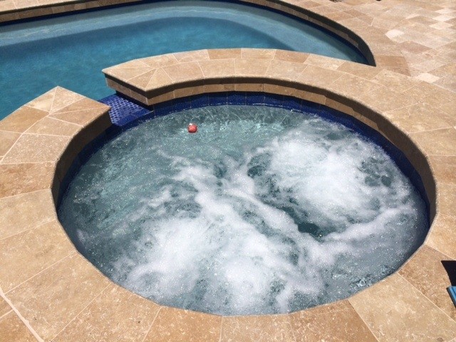 Cette photo montre une piscine à débordement et arrière méditerranéenne de taille moyenne et ronde avec un bain bouillonnant et du carrelage.