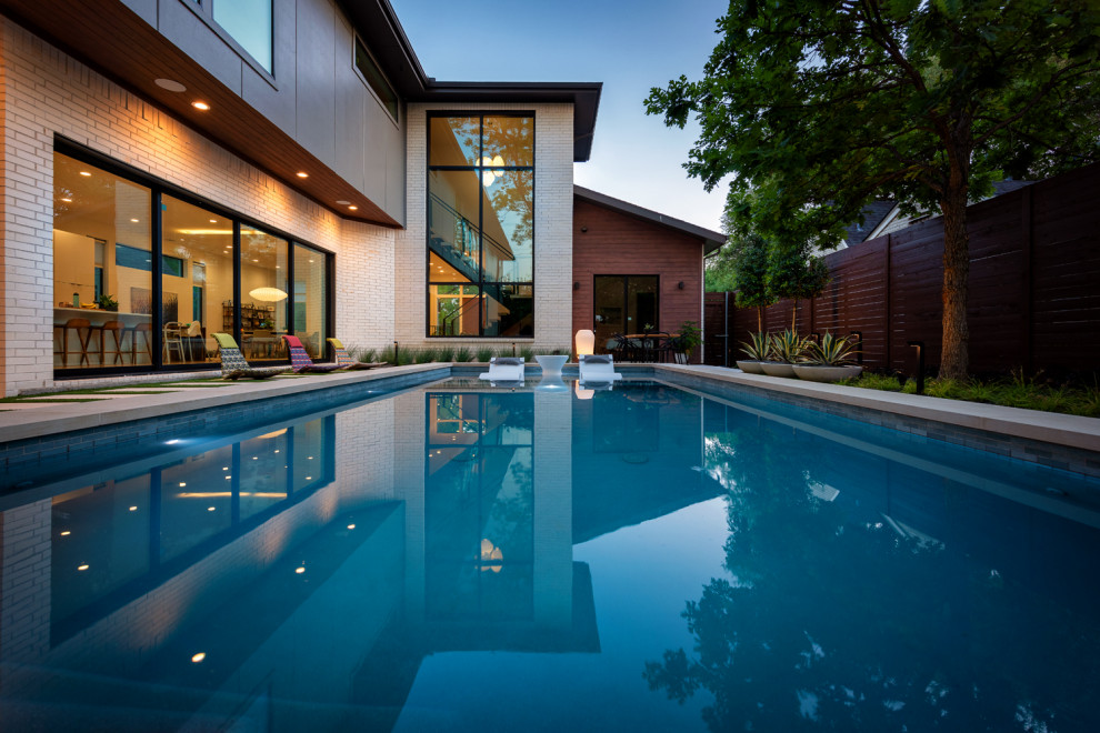 Ispirazione per una piscina minimalista rettangolare di medie dimensioni e dietro casa con pavimentazioni in pietra naturale