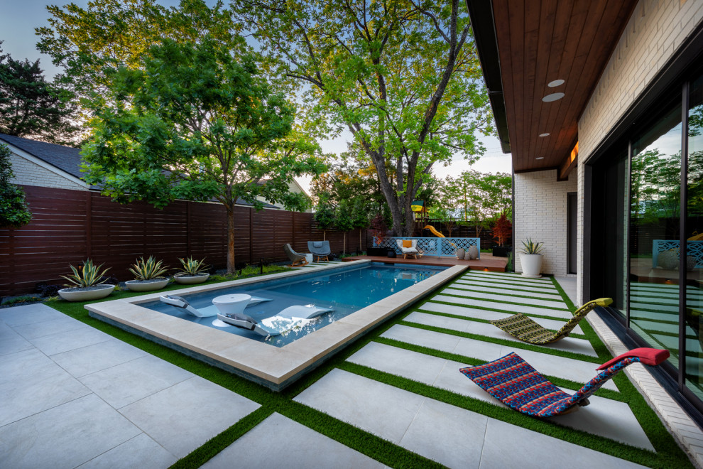 Diseño de piscina moderna de tamaño medio rectangular en patio trasero con adoquines de piedra natural