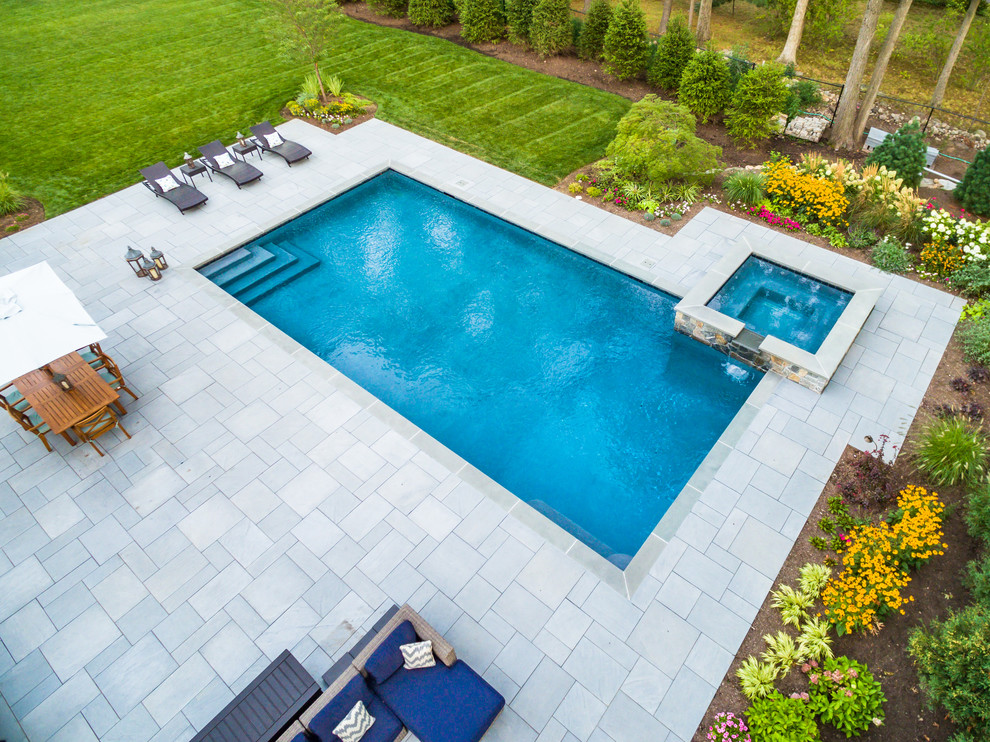 Foto di una grande piscina naturale classica rettangolare dietro casa con una vasca idromassaggio e pavimentazioni in pietra naturale