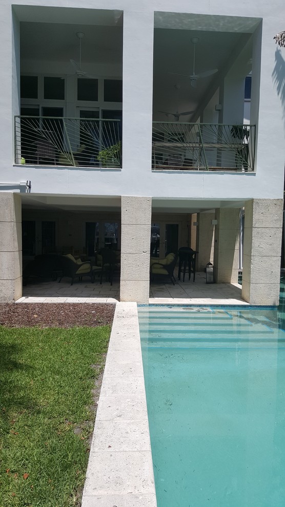 Esempio di una grande piscina design a "L" dietro casa con piastrelle