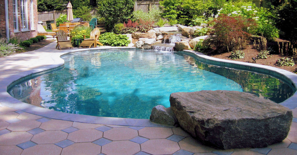 Design ideas for a traditional back custom shaped swimming pool in New York with a water feature.