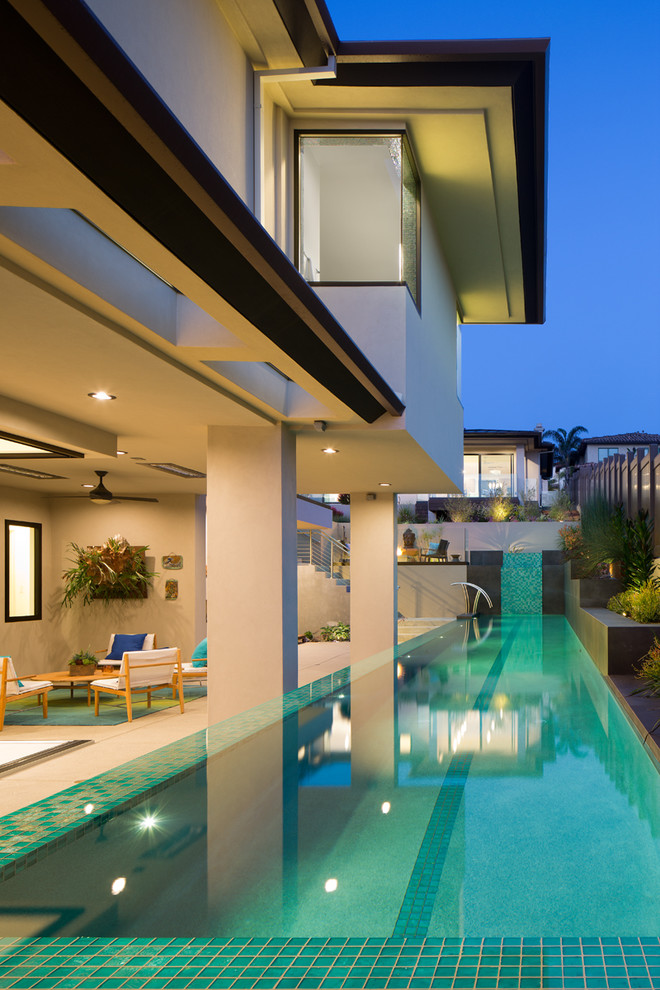 Diseño de casa de la piscina y piscina alargada moderna grande rectangular en patio trasero con losas de hormigón