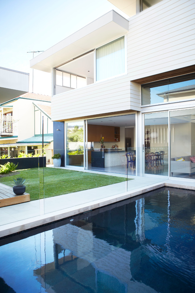 Immagine di una piscina monocorsia minimalista rettangolare di medie dimensioni e dietro casa con pavimentazioni in pietra naturale