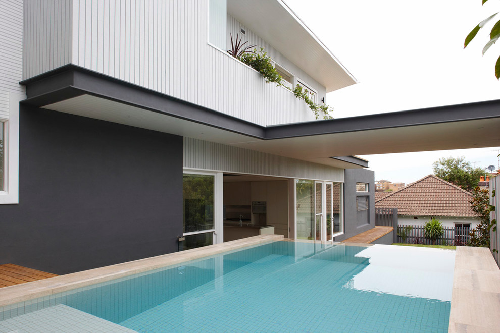 Стильный дизайн: прямоугольный бассейн среднего размера на заднем дворе в современном стиле - последний тренд