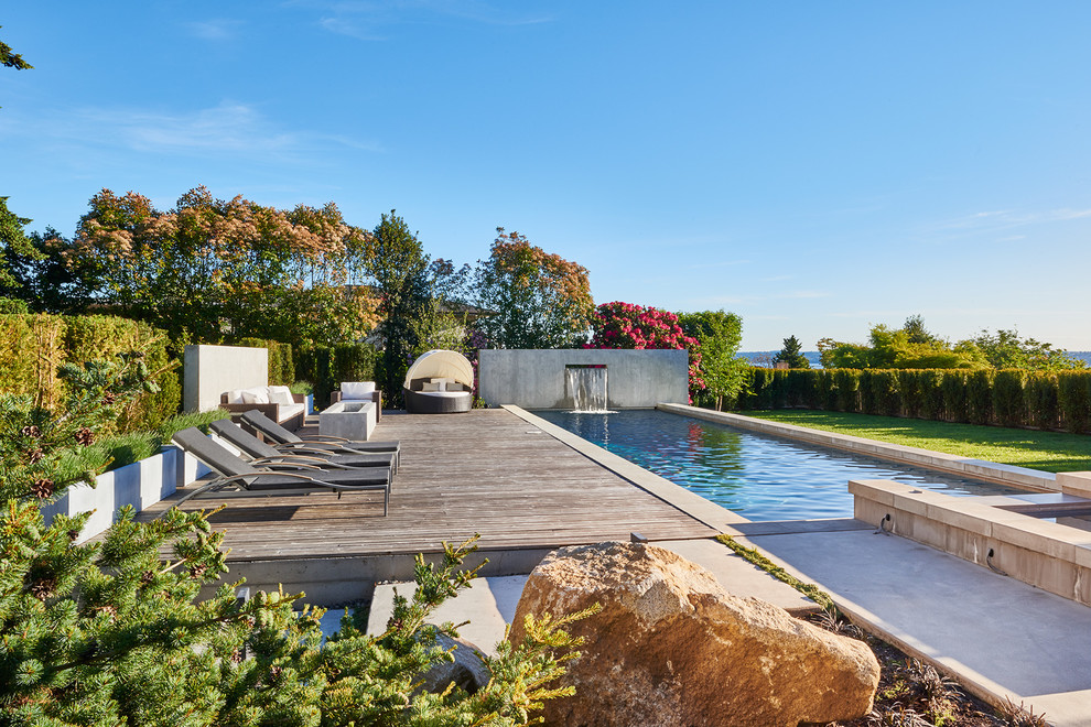 Ispirazione per una grande piscina monocorsia minimalista rettangolare dietro casa con fontane e lastre di cemento