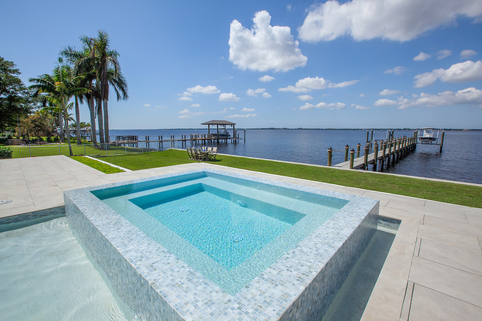 Esempio di una piscina a sfioro infinito minimalista rettangolare di medie dimensioni e dietro casa con una vasca idromassaggio e piastrelle