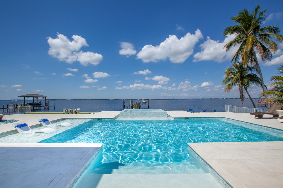 Mid-sized minimalist backyard tile and rectangular infinity hot tub photo in Miami