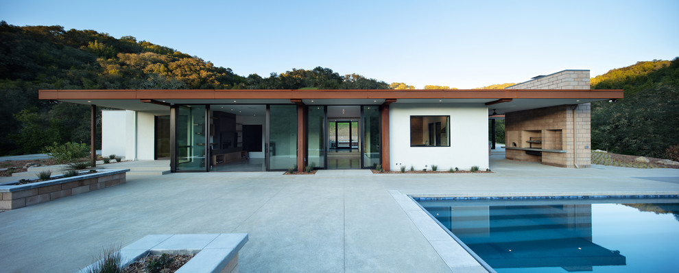 Foto de piscina alargada contemporánea de tamaño medio rectangular en patio trasero con adoquines de hormigón