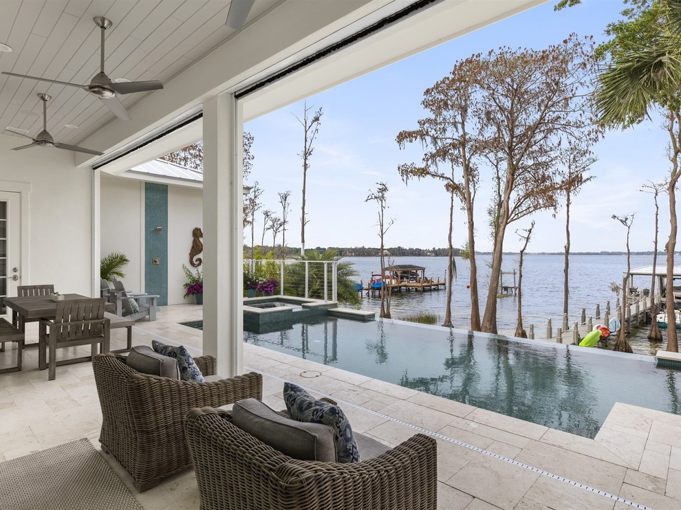 Immagine di una piscina a sfioro infinito stile marino personalizzata di medie dimensioni e dietro casa con una vasca idromassaggio e piastrelle