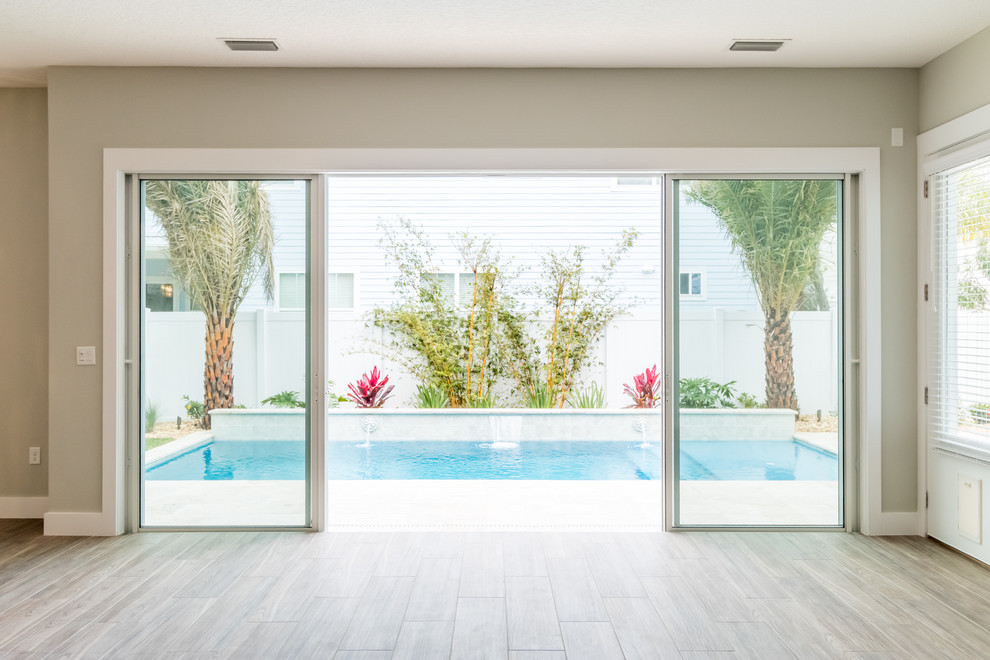 Imagen de piscina con fuente alargada costera de tamaño medio rectangular en patio trasero con suelo de baldosas