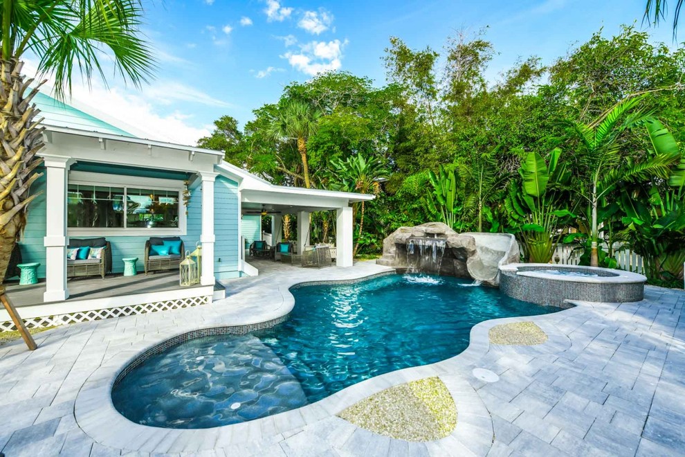 Immagine di una piscina naturale costiera personalizzata davanti casa con pavimentazioni in cemento