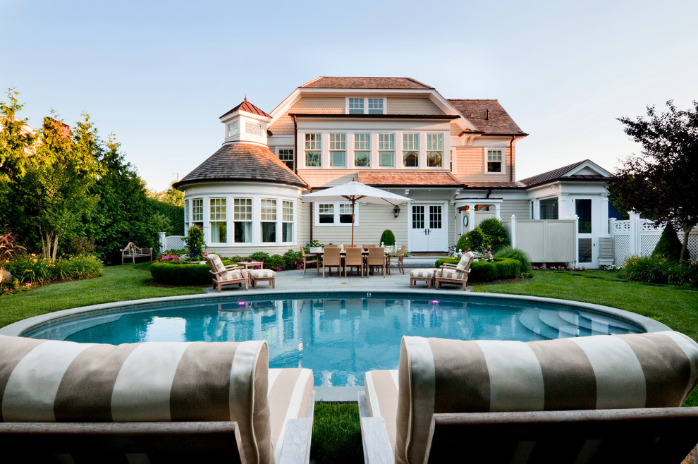 Diseño de piscina alargada costera de tamaño medio redondeada en patio trasero con adoquines de hormigón