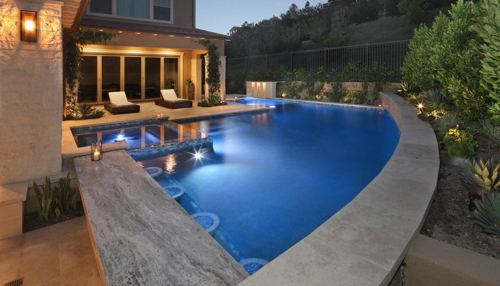 Foto di una piscina costiera a "L" di medie dimensioni con fontane e pavimentazioni in pietra naturale